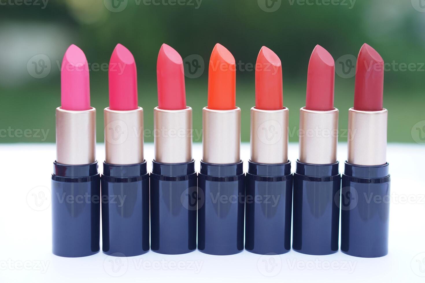 Row of vibrant lipsticks in various shades of pink, orange, and red displayed in elegant black and gold tubes. Concept, beauty, fashion, and makeup diversity, different mood, personality, and style photo