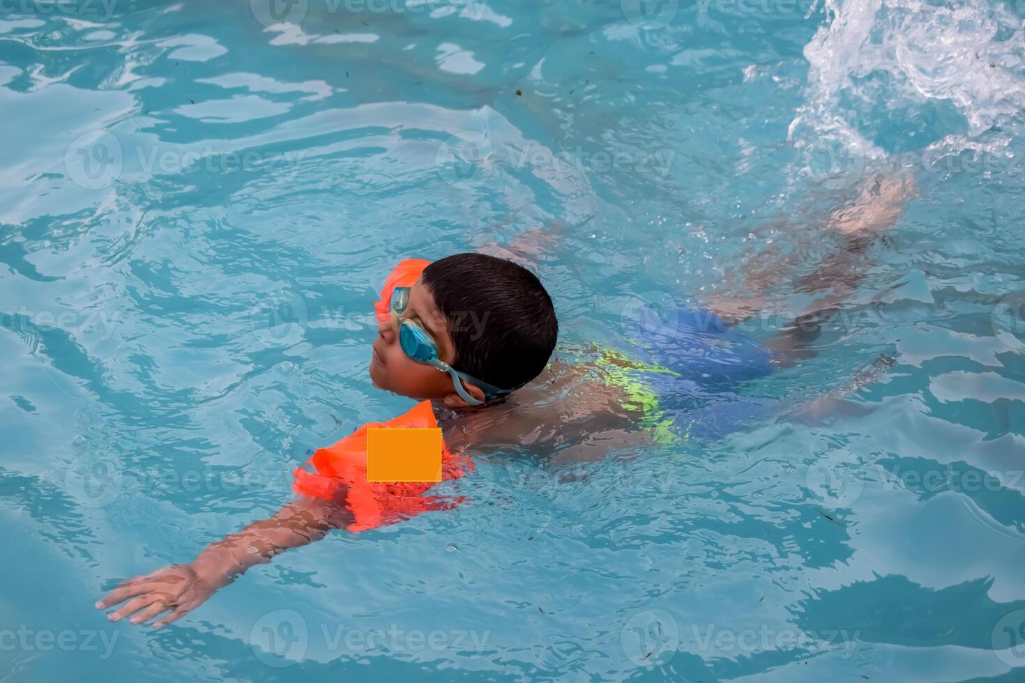 A young boy swimming in a pool with goggles photo