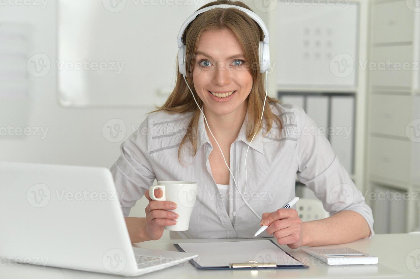 Young business woman with headphones using laptop photo