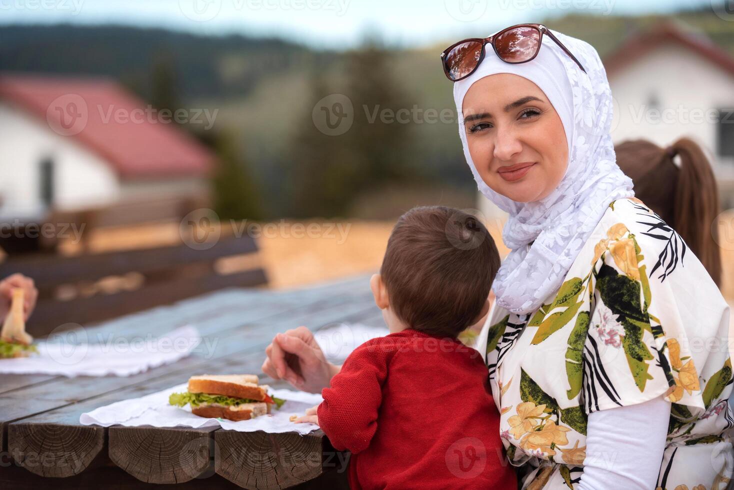 Happy Muslim family eating at a table in the garden. photo