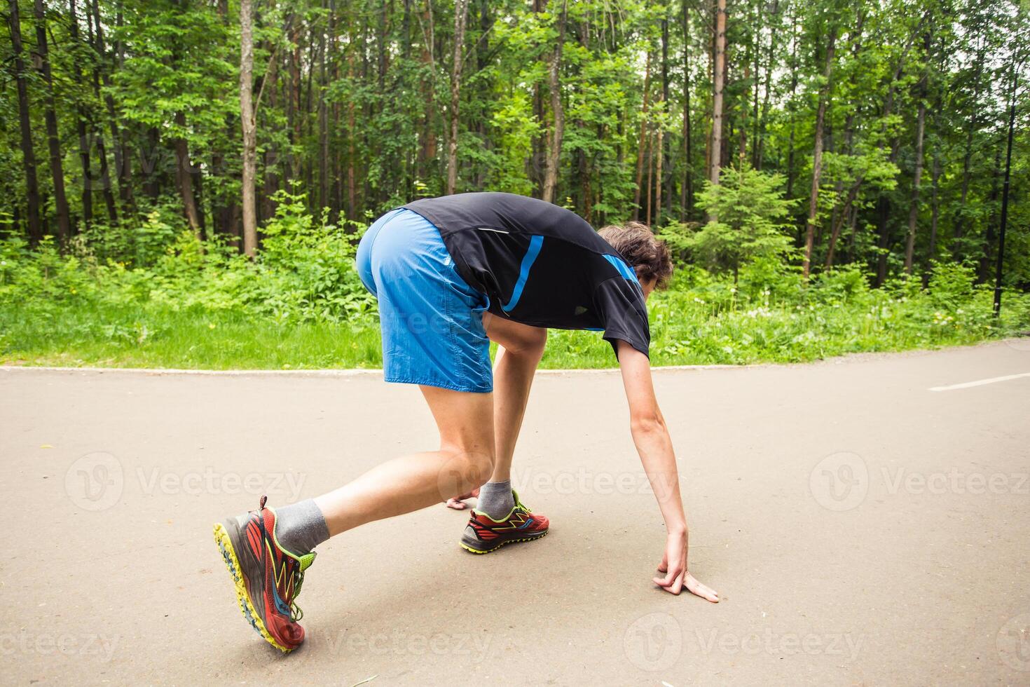 young man runner getting ready for a run on track photo