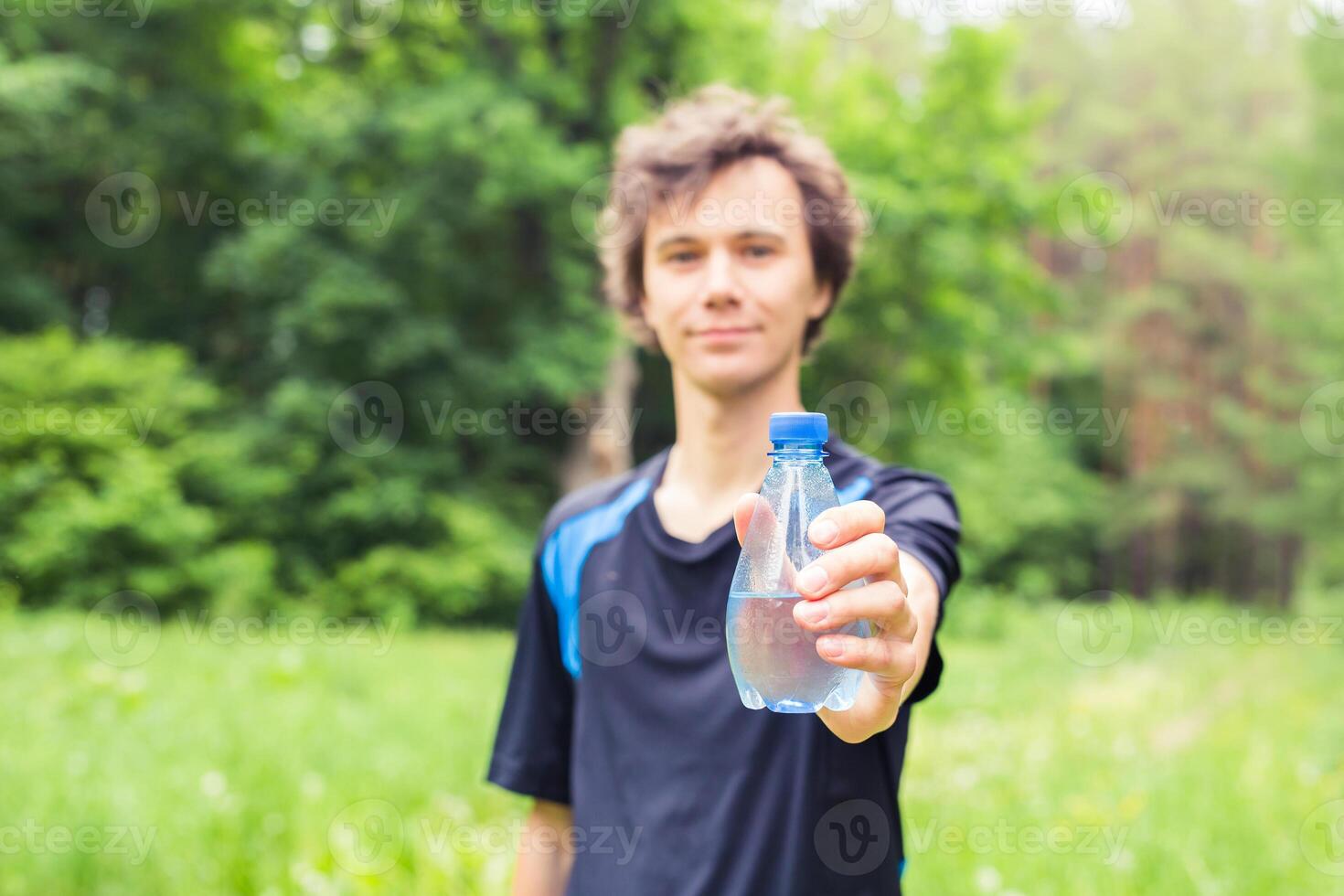 Sportsman with a bottle of water after running outdoors in park. photo