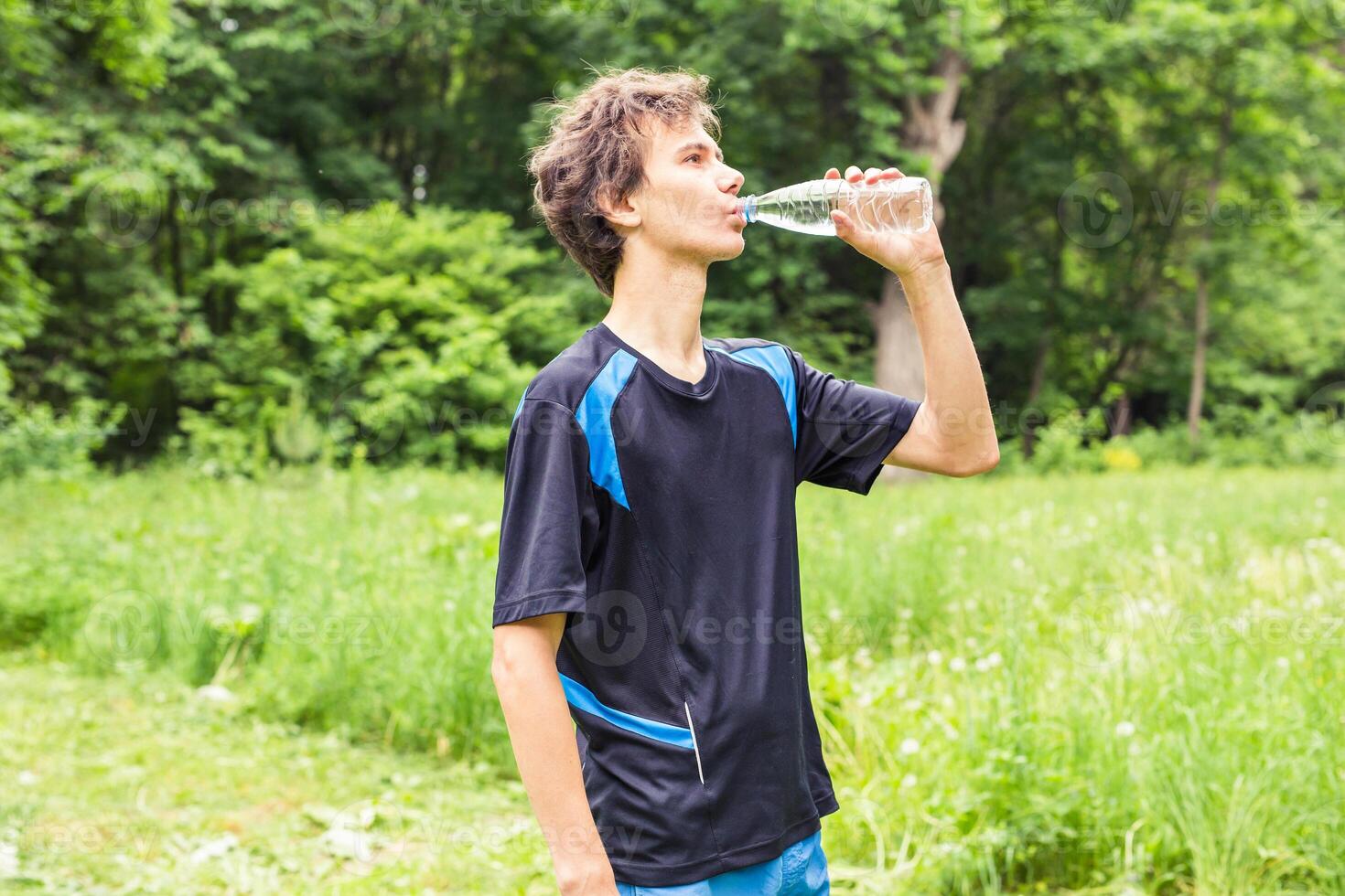 close up of a man drinking water from bottle outside photo