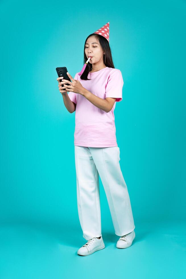 Portrait of Happy Young Asian Woman Celebrating Birthday With Smartphone photo