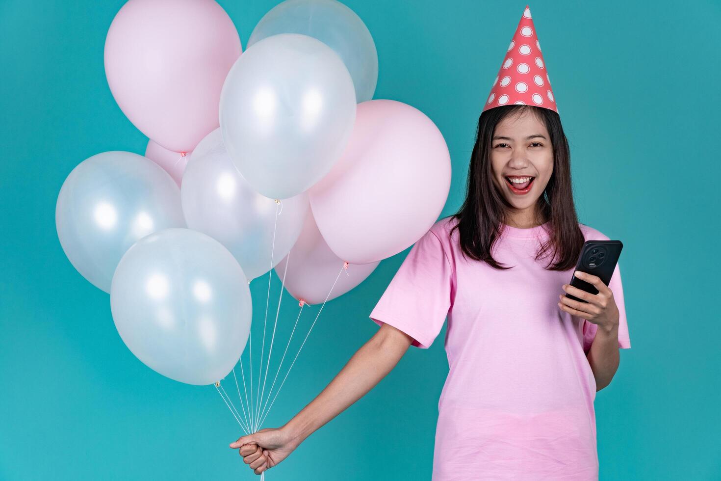 Portrait of Happy Young Asian Woman Celebrating Birthday Holding Smartphone Background photo