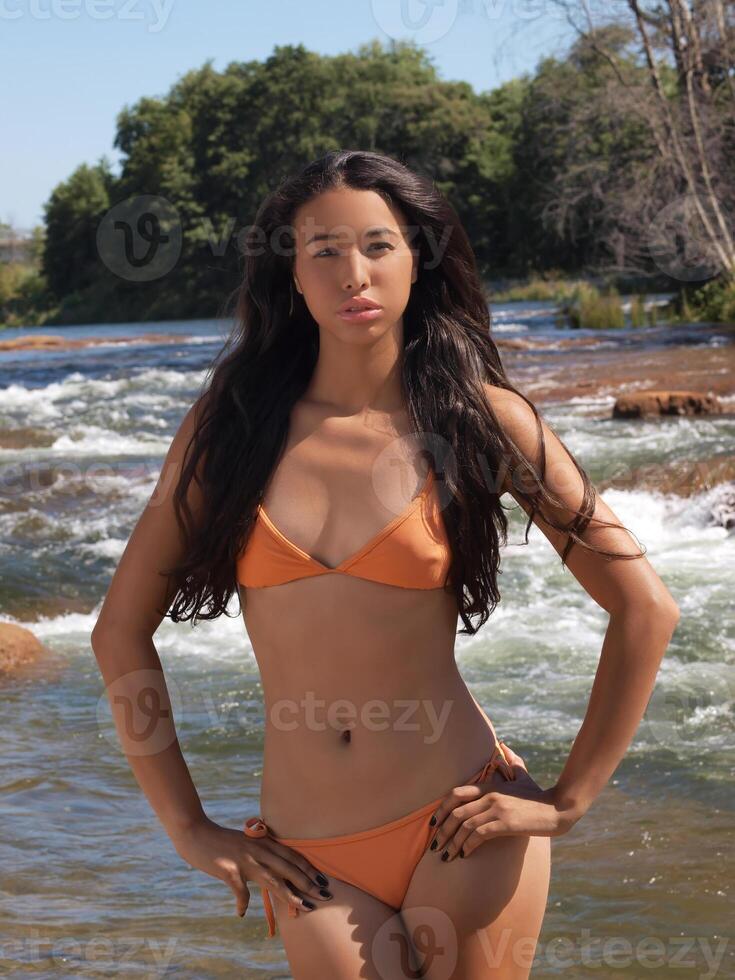Attractive Young Hispanic Woman Standing In Orange Bikini At River photo