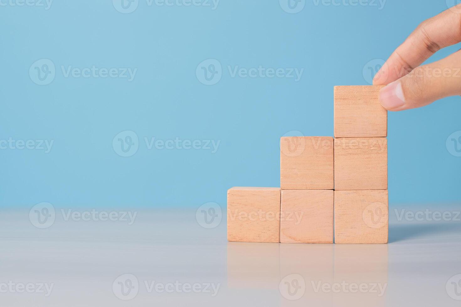 Man's hand organizing wooden blocks on blue surface. Symbolizes workflow, step-by-step strategy, or structure photo