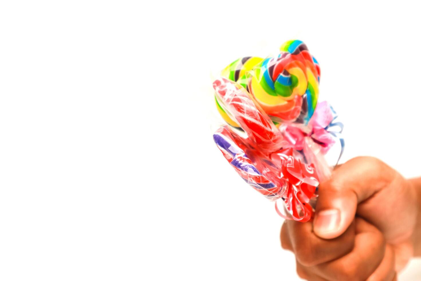 Hand holding a bundle of colorful lollipops against a plain white background, perfect for a sweet treat advertisement photo