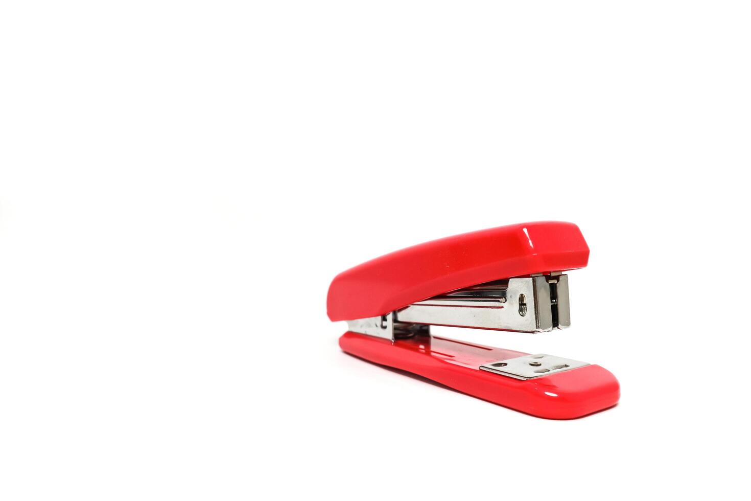 Studio shot of a bright red stapler isolated on a clean white background, representing office supplies photo