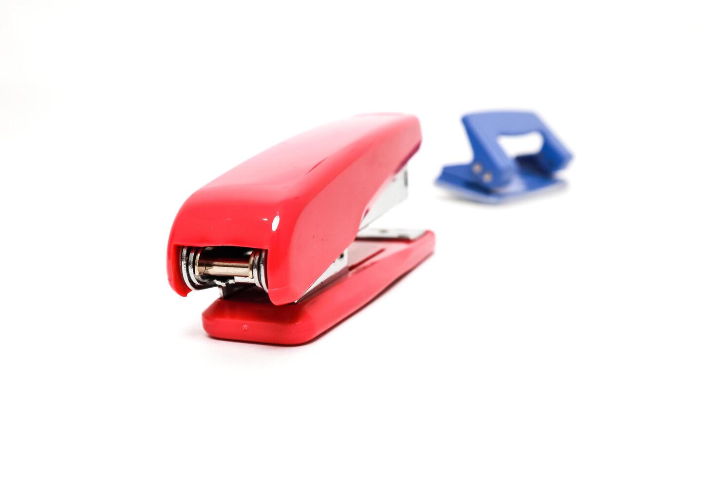 Red stapler and blue hole punch on a white background, perfect for office and stationary concepts photo