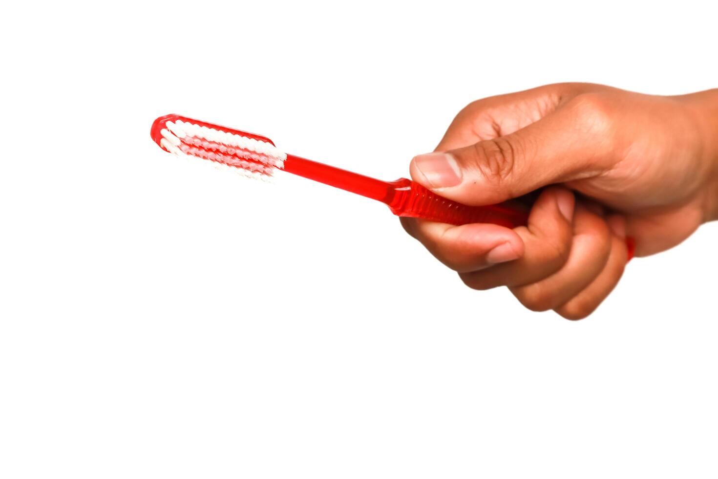 Hand holding a red toothbrush on a white background for oral hygiene education photo