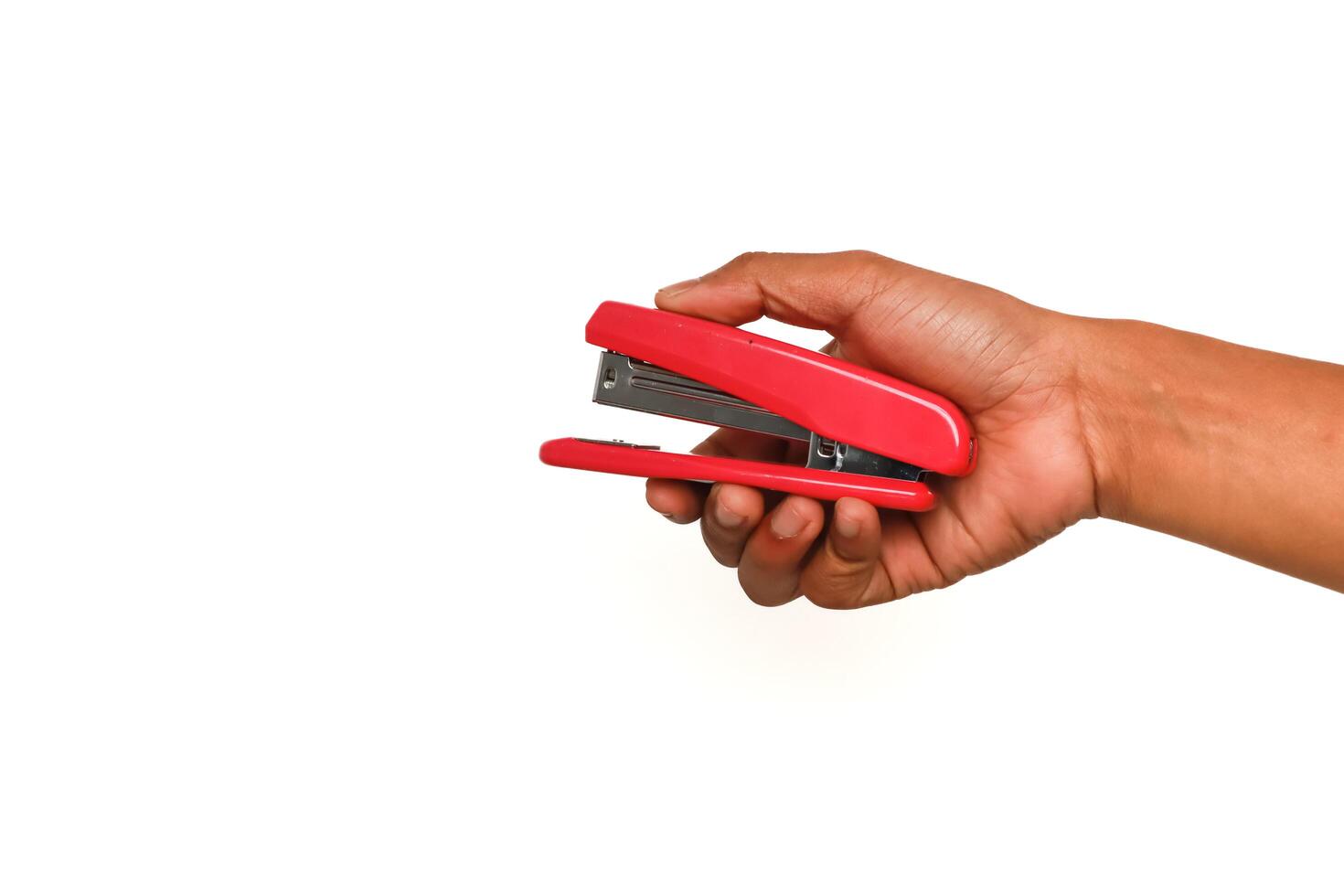 Hand holding a bright red stapler isolated on a clean white background, ready for office use photo