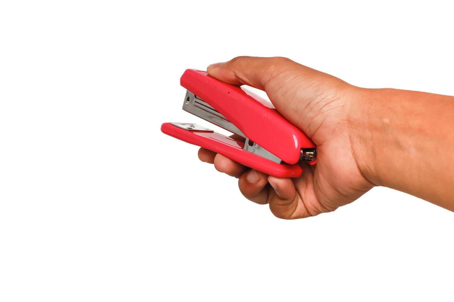 Close-up of a hand holding a red stapler ready to staple papers, isolated on white photo