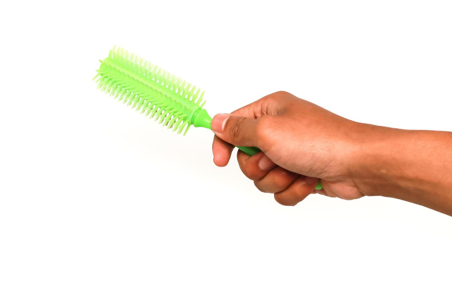 Hand holding a green hair brush against a clean white background studio shot photo