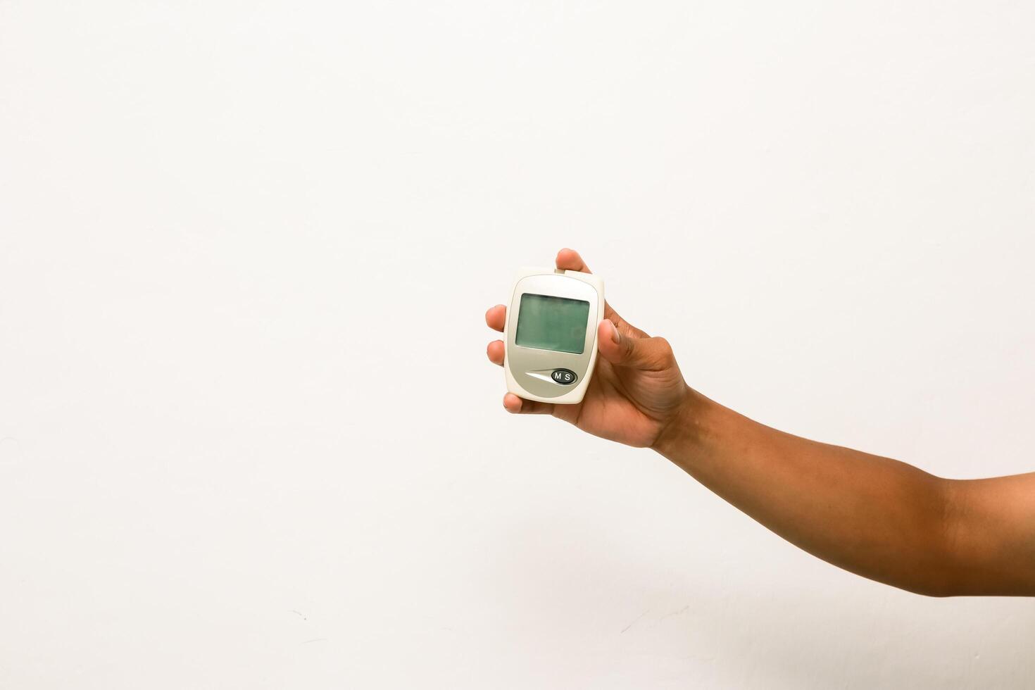 Hand holding glucose meter for checking blood sugar levels, diabetes control and monitoring concept, white background photo