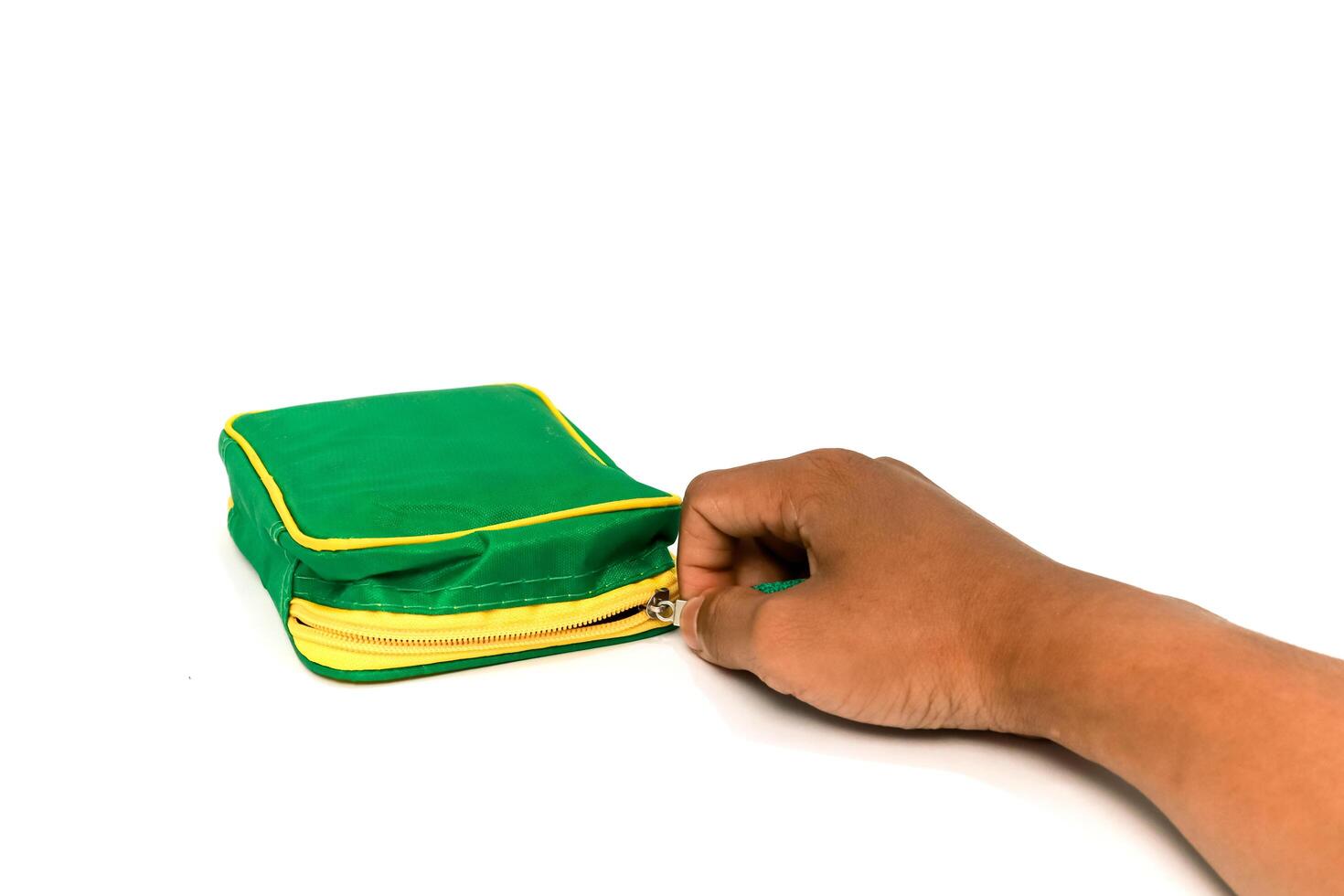Hand opening a green and yellow zippered pouch on a clean white surface, product shot photo