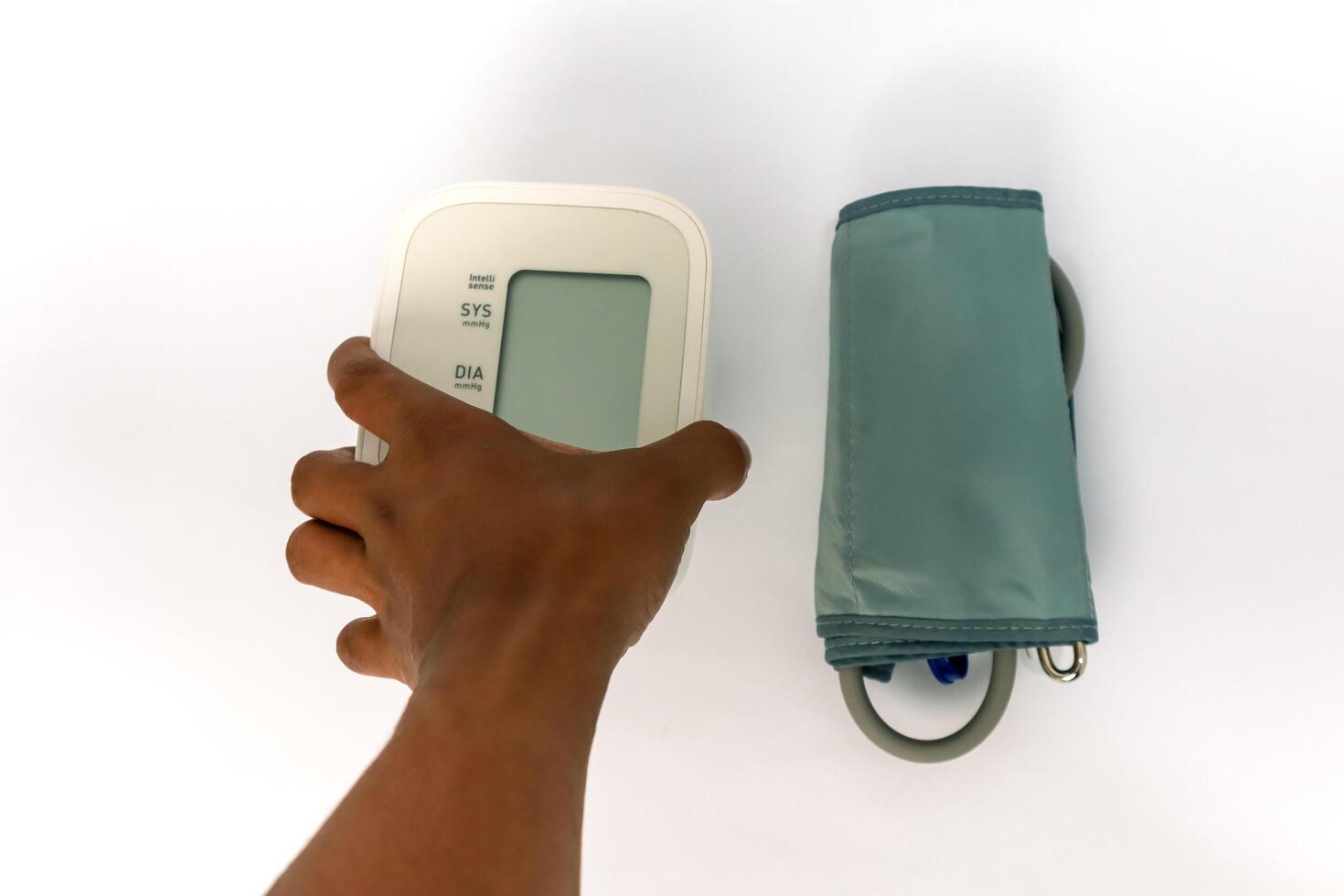 Close up of a hand holding an electronic blood pressure monitor against a white background photo