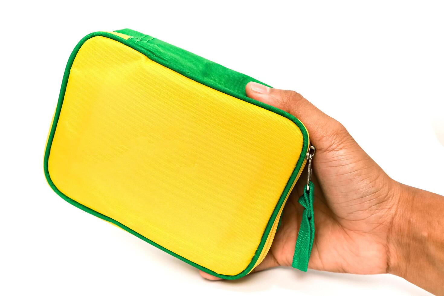 Hand holding a bright yellow and green rectangular cosmetic or travel pouch on white photo