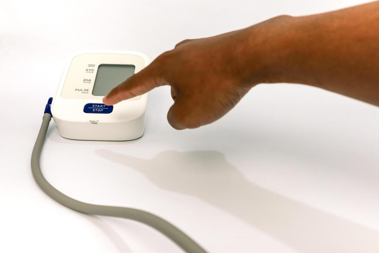Close-up of a finger pressing the start button on a blood pressure monitor on a white background photo