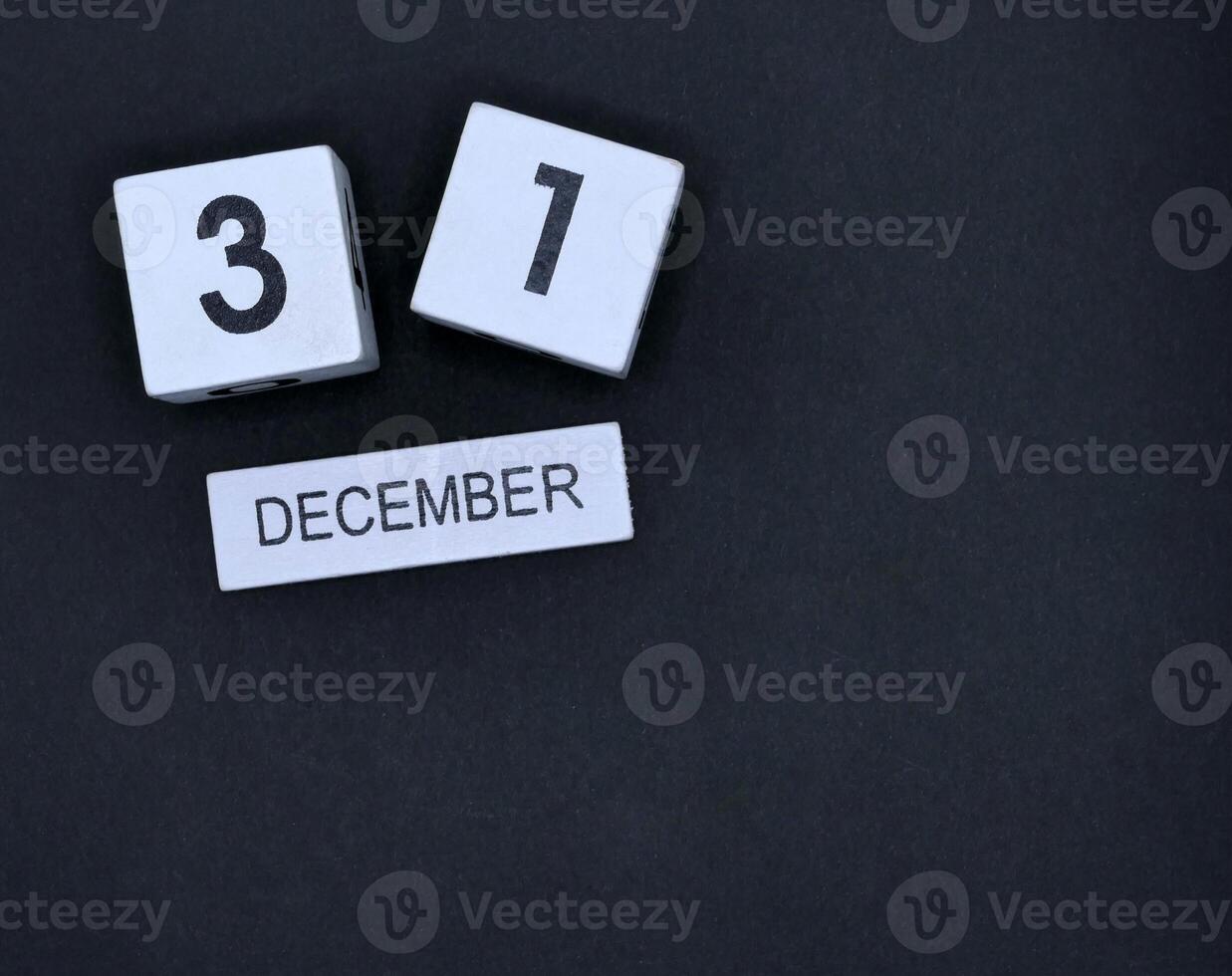 Wooden calendar, December 31st, New Year's Eve on black background photo