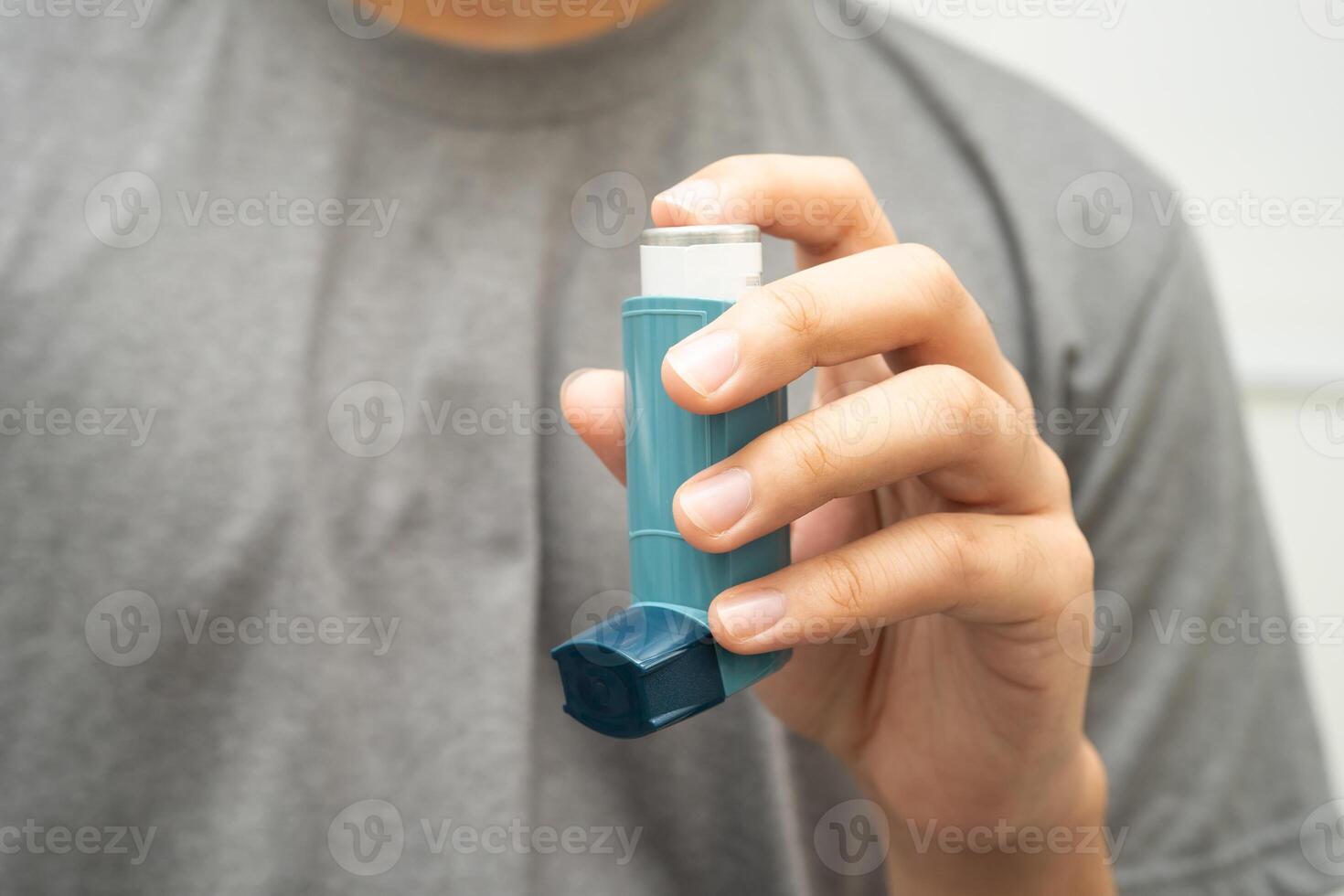 Asthma chronic obstructive pulmonary disease COPD, Asian young man using metered dose inhaler MDI. photo
