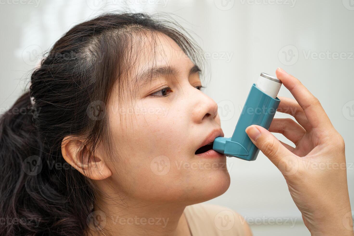 Asthma chronic obstructive pulmonary disease COPD, Asian woman using metered dose inhaler MDI. photo