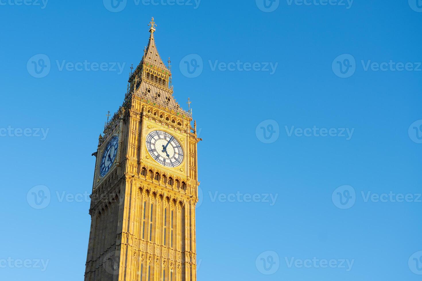 Big Ben towers majestically against a bright blue sky. This iconic clock tower, located in London, showcases its detailed architecture and historical significance. photo