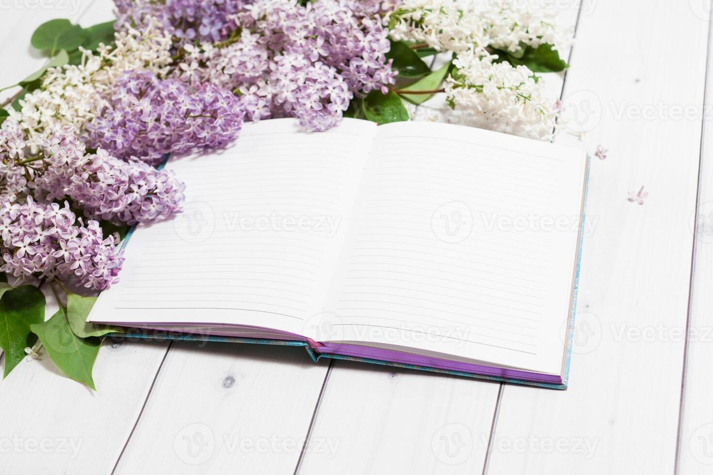 Lilac flowers with opened note book on the wooden white horizontal background photo