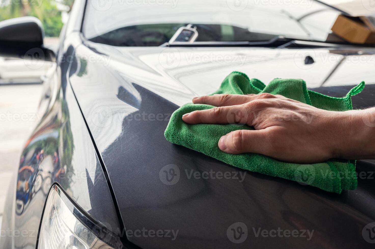 Hand man with green microfiber cloth wiping on car hood photo