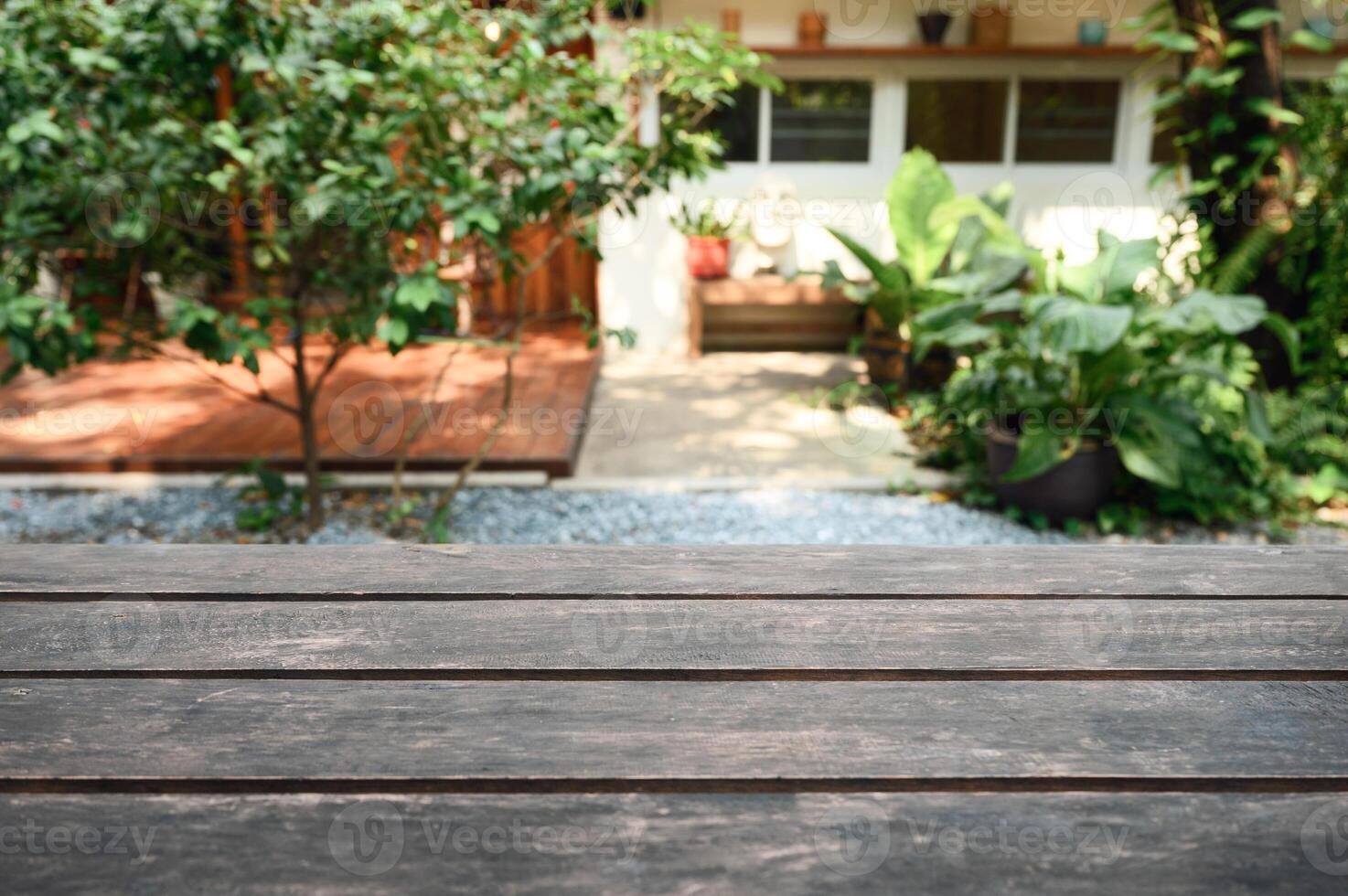 Rustic brown wooden table top on blurred green plant in garden backyard photo