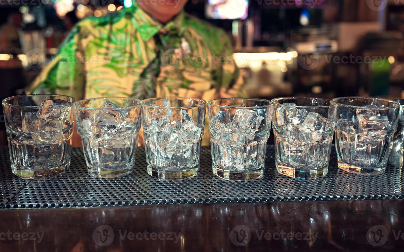 Cocktail glass with ice cubes on counter bar in nightclub photo