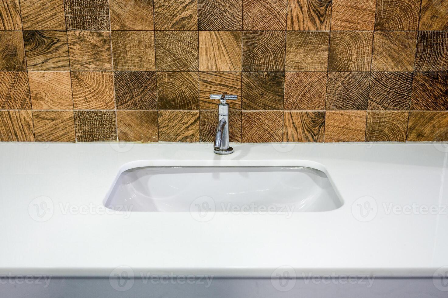 Silver Water tap with white ceramic basin on wood tiles photo