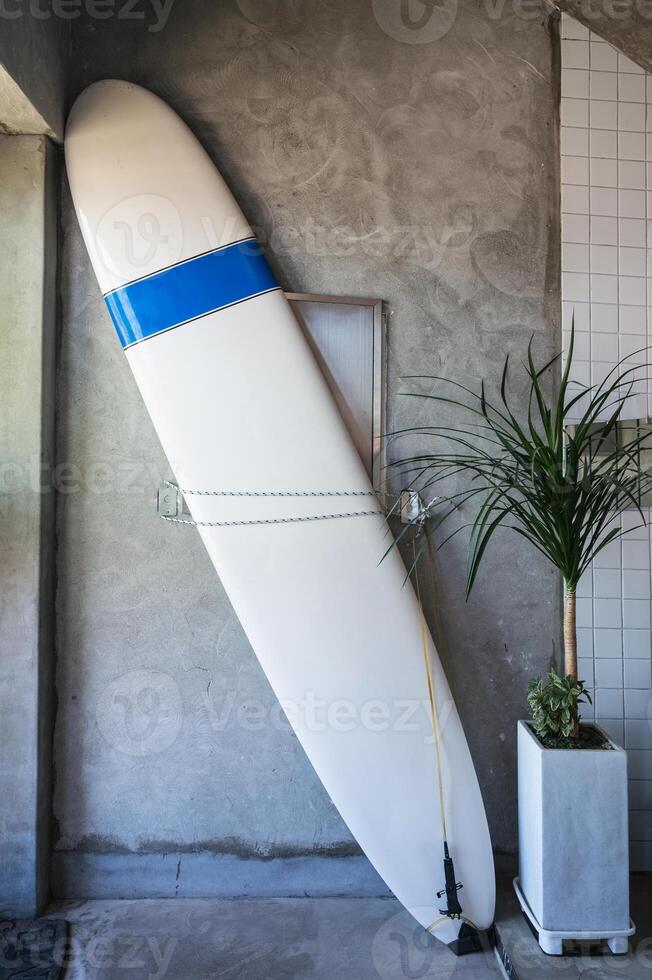 White surfboard leaned against on cement wall photo