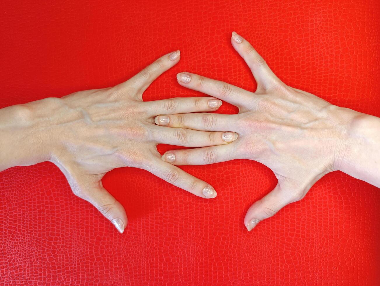 Hands with elongated fingers positioned on a vibrant red background showcasing unique formations in a creative display photo