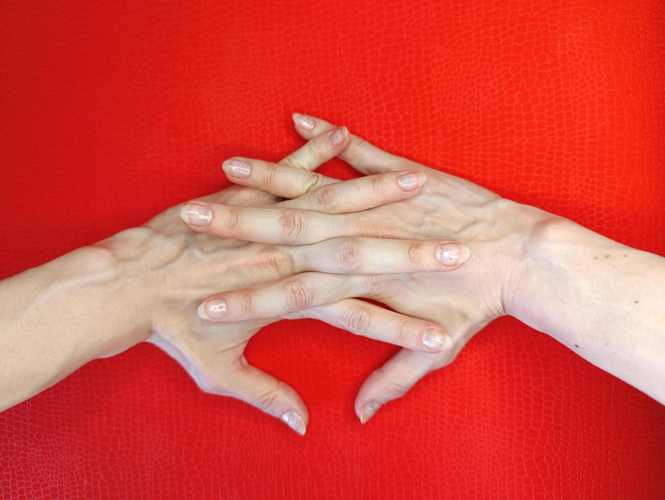 Intricate hand gesture on a vibrant red background, showcasing delicate fingers and contrasting skin tones photo