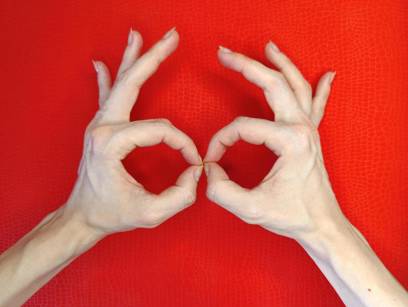 Hands forming a heart shape against a vibrant red background during a creative art session photo