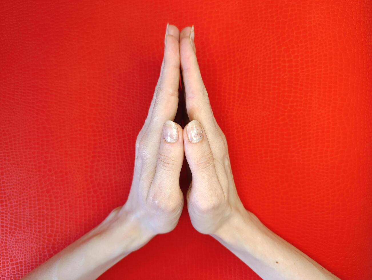 Hands in prayer position on vibrant red background symbolizing peace and tranquility during meditation practice photo