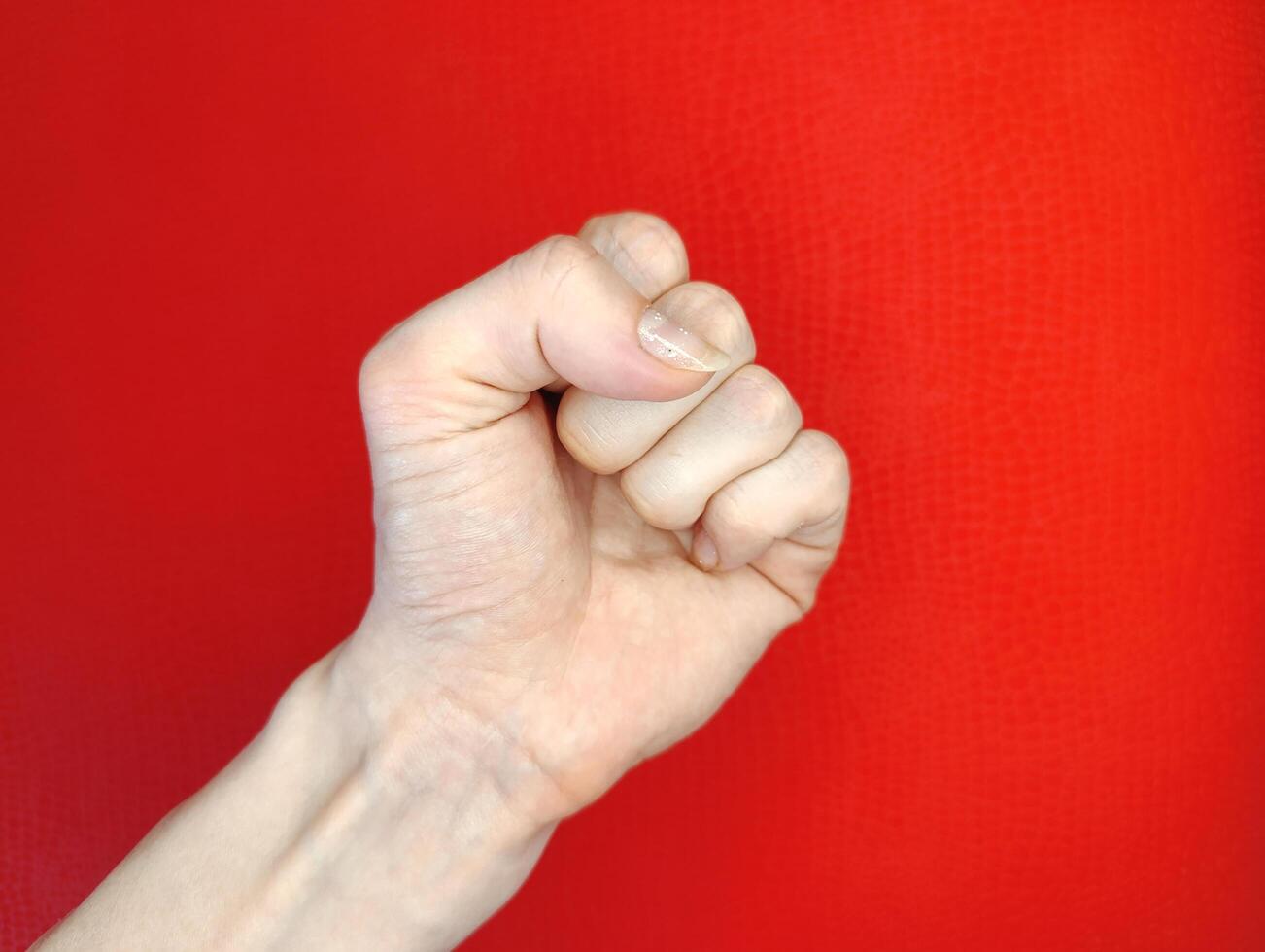 Fist held firmly against a bright red background expressing strength and determination during an empowering moment photo