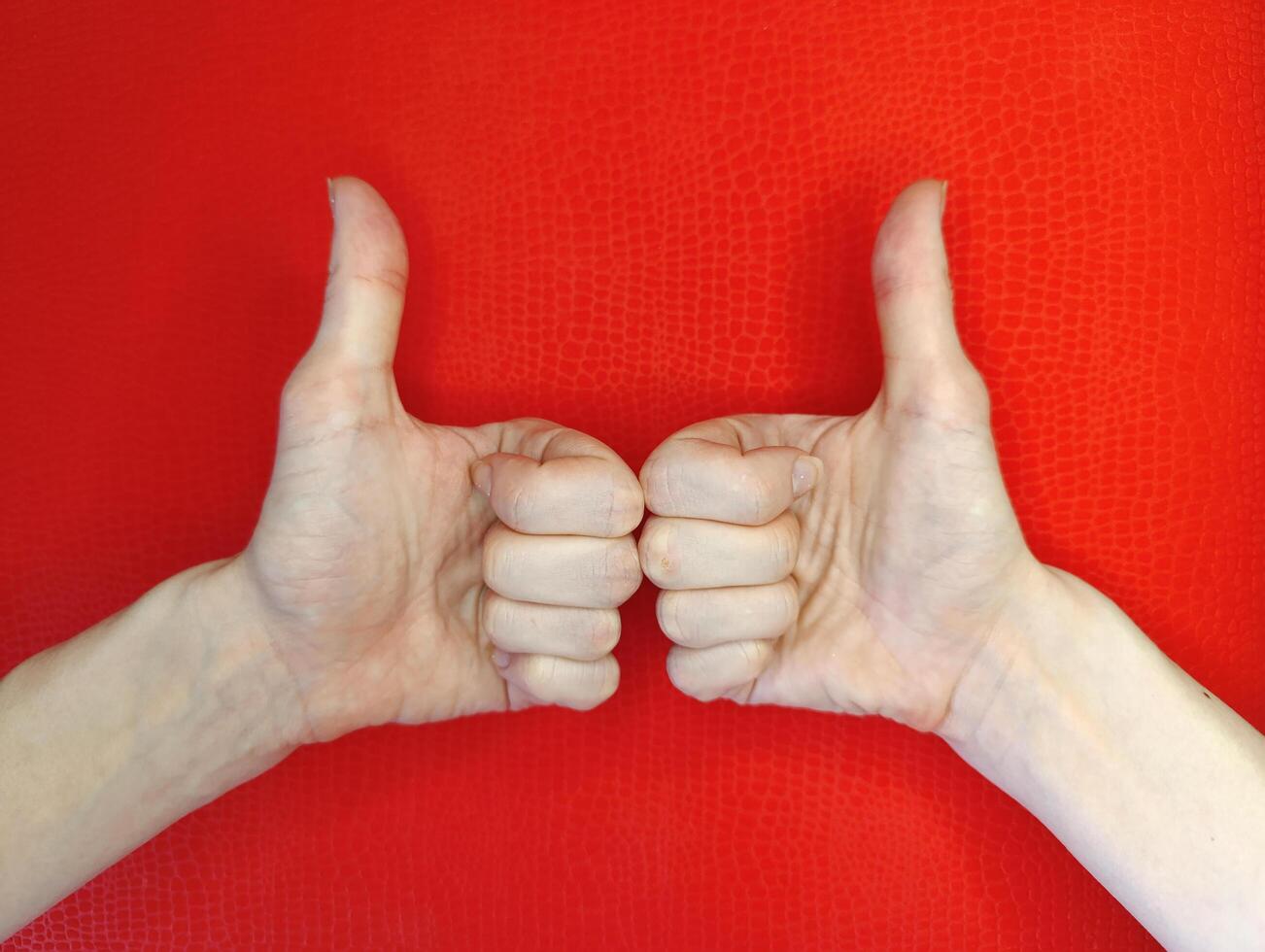 Hands giving a thumbs up gesture against a vibrant red background celebrating positivity and approval photo