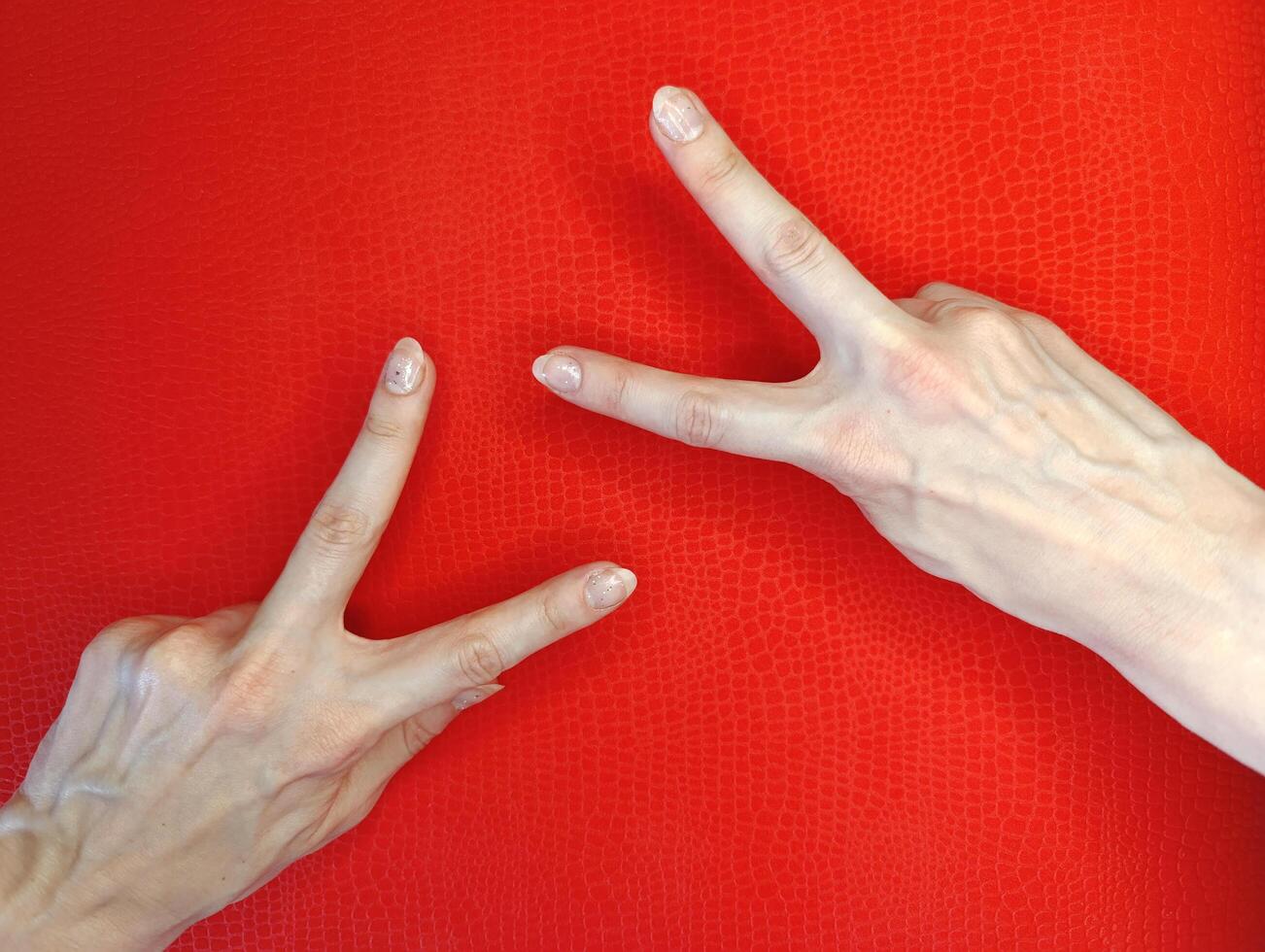 Hands forming peace signs against a vibrant red background displaying creativity and expression photo
