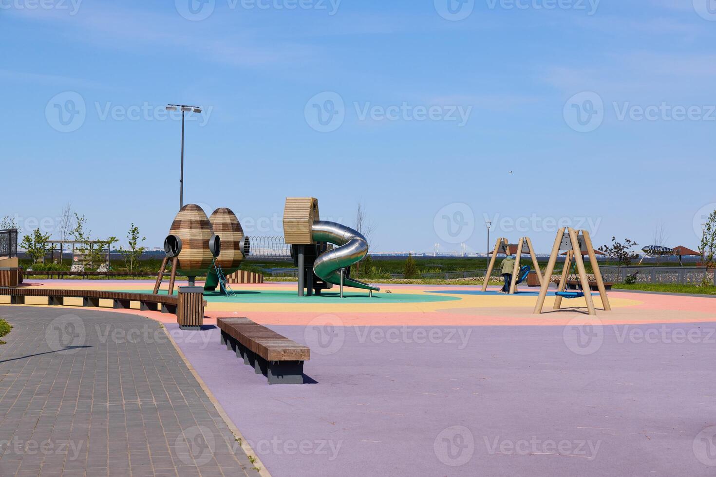 A Vibrant and Colorful Playground Featuring a Slide and Swings on a Bright Sunny Day photo