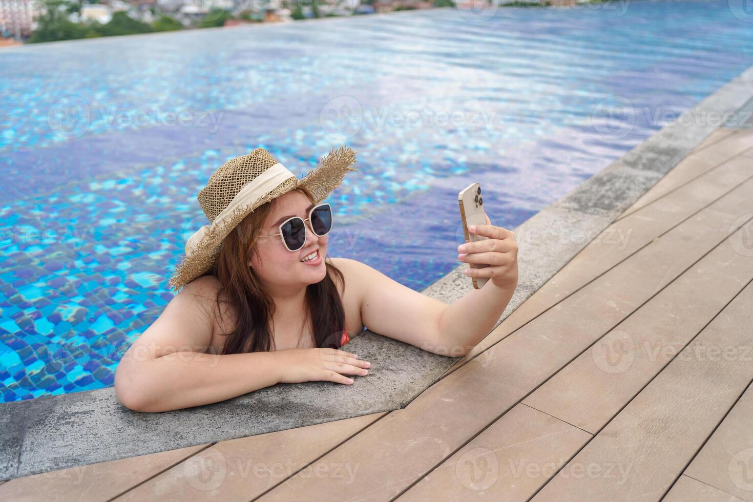 a obese woman in a hat and sunglasses taking a selfie in a pool photo