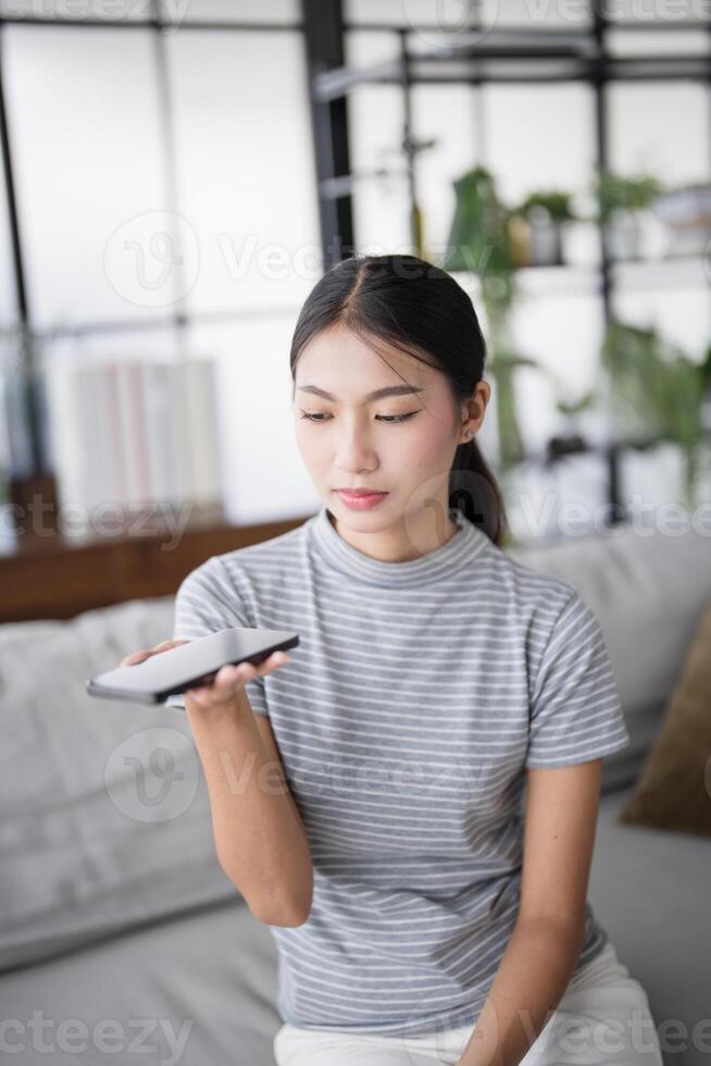 woman using smartphone while sitting on couch at home. photo