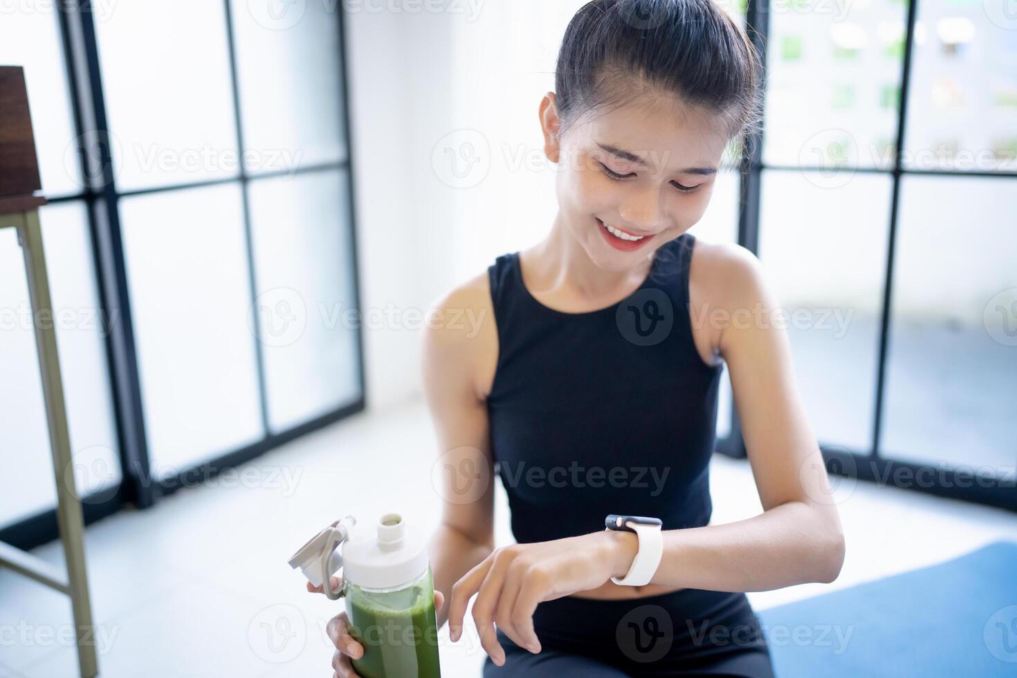 a sporty woman is holding a green smoothie in her hand photo