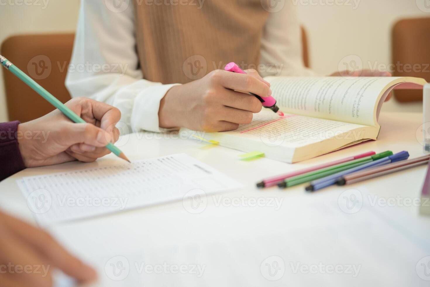 Learning with friends a person is writing on a book with a pencil photo