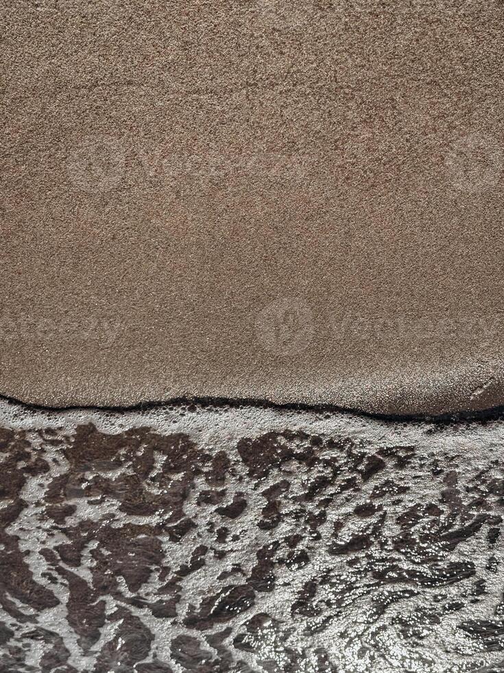 Peaceful beach moment with a soft wave gently touching smooth sand captured in warm light perfect for backgrounds textures and themes of simplicity calm and coastal peace photo