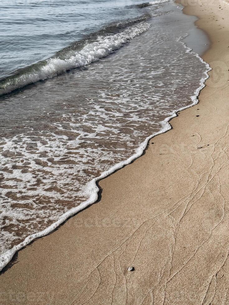 Soft sea foam reaches untouched sand creating a peaceful border between water and earth perfect for themes of balance mindfulness and slow living at the coast photo