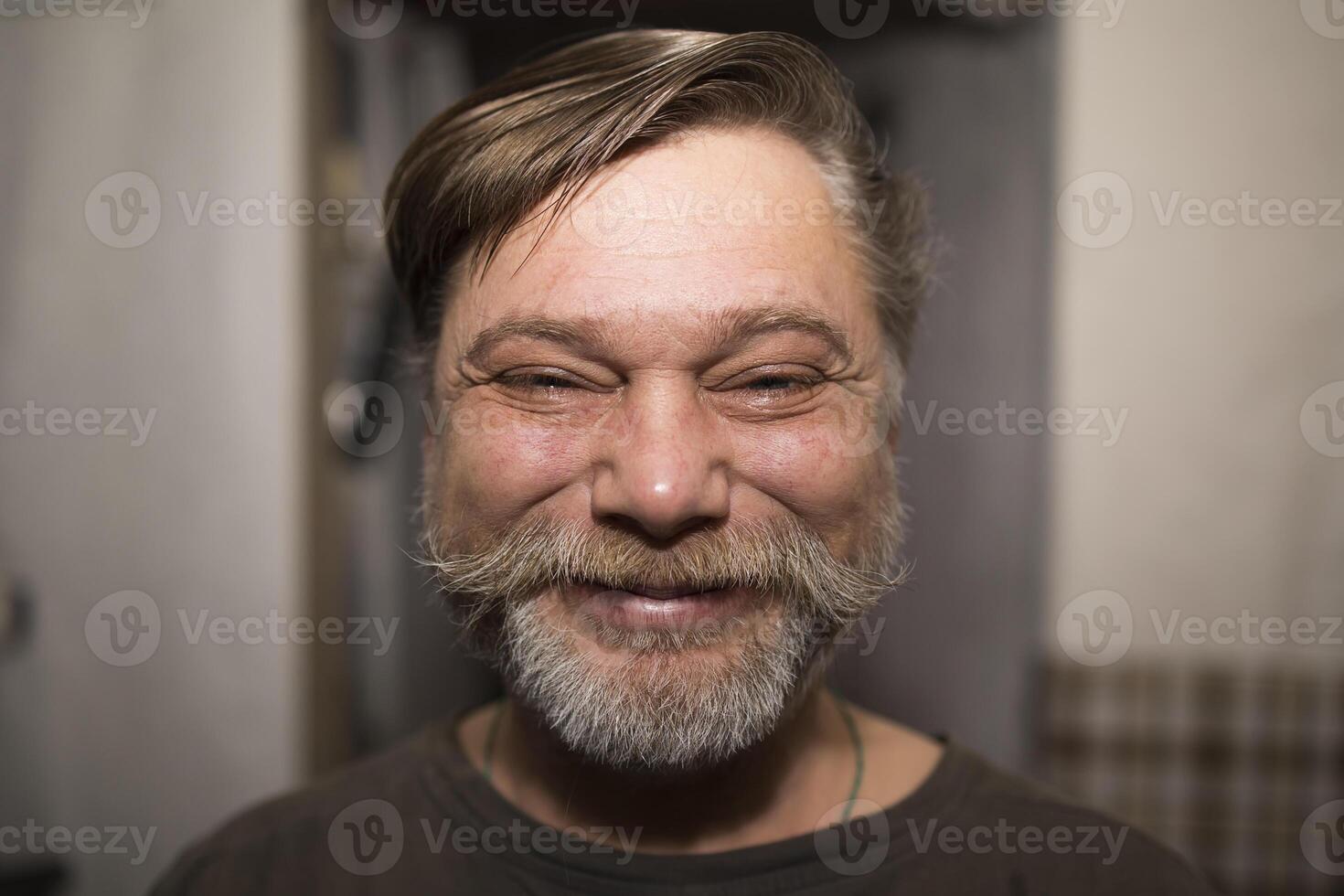 A man with a beard and mustache is smiling happily for the camera photo