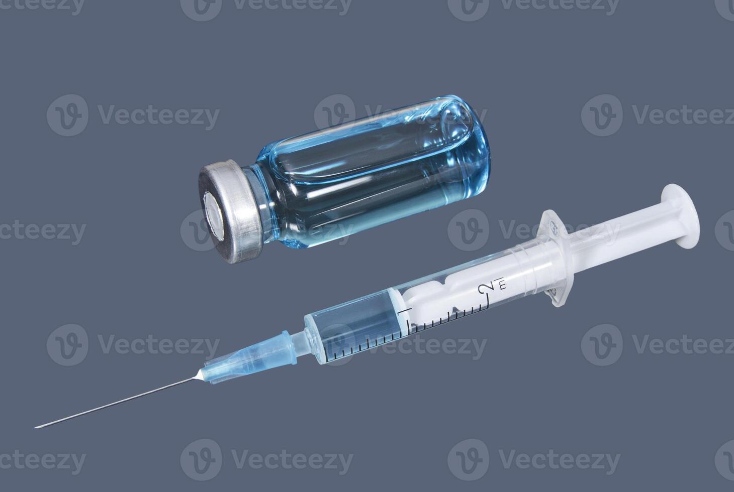 Syringe and phial with blue vaccine on the dark background photo