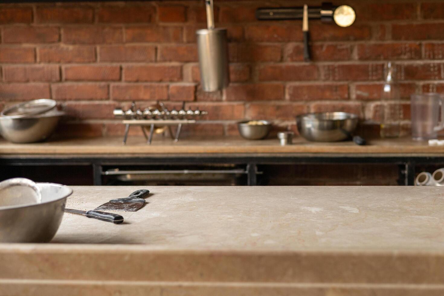 Kitchen countertop with metal cookware and tools arranged neatly against a brick wall photo